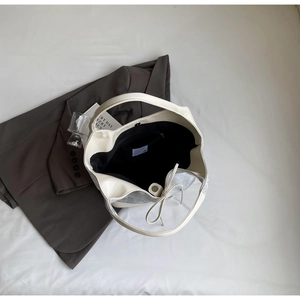 Detail of a large cream and grey bucket bag with magnetic closure and interior zipper pocket