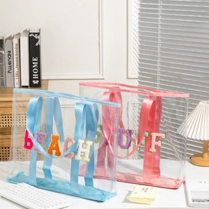 Large transparent PVC tote bags with colorful chenille letter patches and webbed handles