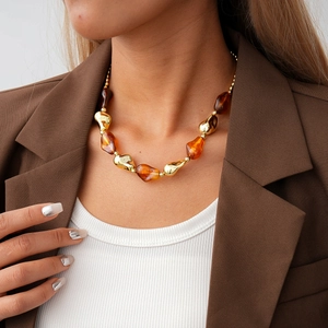 Detail of chunky acrylic amber and gold geometric bead necklace on a professional model