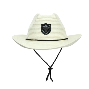 Detail of cream woven cowboy hat featuring metal bull head patch and adjustable chin strap