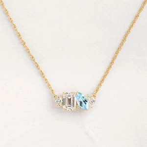 Elegant gold necklace featuring emerald-cut clear stone and marquise-cut light blue gem