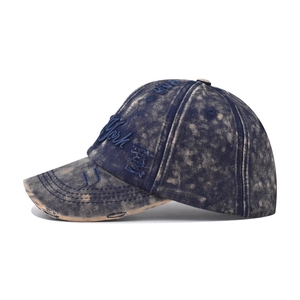 Detail of distressed denim baseball cap with York embroidery and acid wash finish
