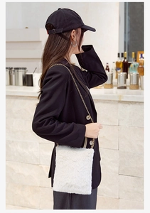 Minimalist white plush crossbody bag with metal chain shown on a black blazer