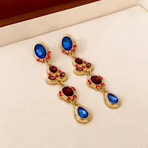 Vintage style drop earrings with blue teardrop stones and red crystals in gold finish