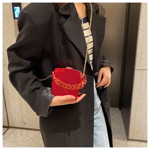 Detail of red glossy hard shell mini bag with thick chain handle and metal strap
