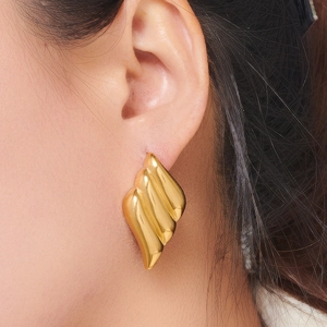 Minimalist wing-shaped golden earrings with textured leaf design shown on model
