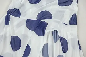 Close-up of white chiffon fabric with large navy polka dots and stitched seam detail