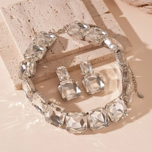Macro shot of silver square crystal necklace and earrings set on a textured stone base