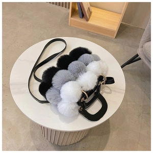 Detail showing plush tricolor faux fur balls and leather strap on a stylish handbag