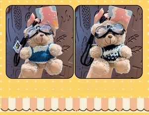 Detail view of plush brown bear keychains wearing goggles and knitted blue sweaters