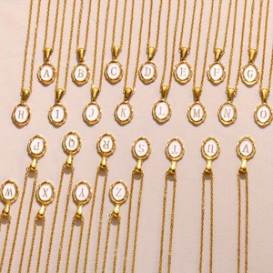 Macro view showing the full collection of twenty-six gold letter pendants with white enamel