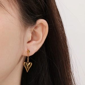 Close-up of a polished golden heart-shaped earring worn by a model in a minimal setting
