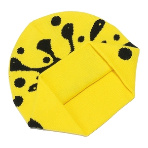 Detailed close-up of thick knitted fabric texture and black pattern on yellow beanie hat
