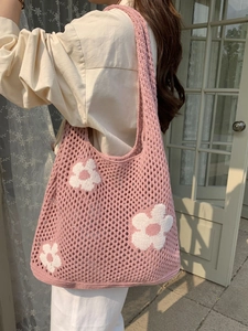 Detail einer rosa Stricktasche mit weißen Blumenmustern an der Schulter eines Models