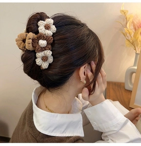Detail of woven wool flower hair claw with knit texture in cream and caramel tones