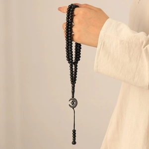 Detail of 99 beads Islamic Tasbih with star and moon charms held by a model
