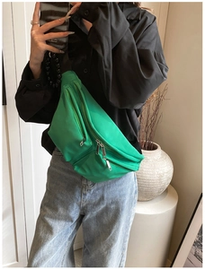 Bright green nylon crossbody fanny pack with triple zipper layers on a female model