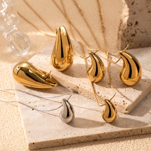 Minimalist gold and silver hammered teardrop earrings and necklace set on stone background