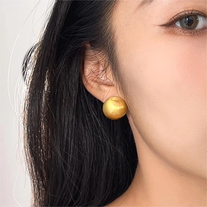 Minimalist matte gold semi-sphere stud earrings shown on a model's ear profile