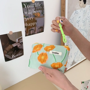 Detail view of mint green cosmetic bag with orange floral print and neon rope zipper