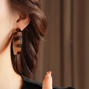 Detailed view of bohemian hoop earrings with natural layered wood textures on a model