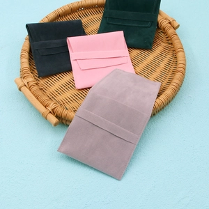 Detail of four colorful velvet jewelry pouches in a round woven tray with envelope flaps