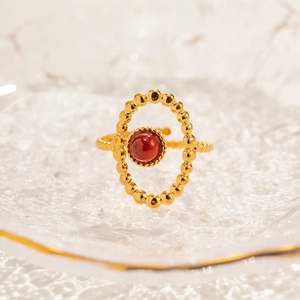 Detail of vintage gold ring with oval red bead stone in luxury hammered glass tray