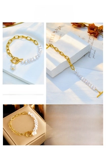 Detail of gold chain and pearl bracelet with OT toggle clasp on a decorative background