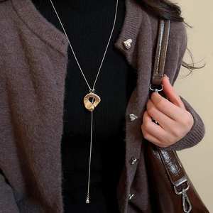 Minimalistische goldene lange Halskette mit geometrischem Anhänger auf Strickware