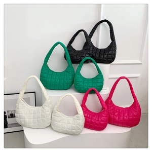 Quilted dumpling shoulder bags in four colors and two sizes on a minimalist display stand