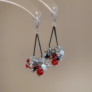 Détail de boucles d'oreilles bohèmes à pompons avec perles colorées et zircon