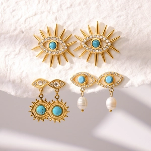 Detailed view of gold evil eye earrings featuring turquoise, crystals and baroque pearls