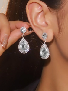 Macro detail of teardrop earrings featuring sparkling rhinestones on a female model