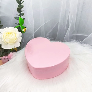 Caja de regalo rosa con forma de corazón y acabado brillante sobre piel sintética blanca