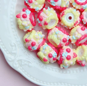 Macro shot of colorful hand-painted acrylic beads for DIY jewelry on a white relief plate