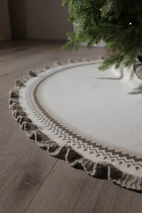 Detail of knitted cream Christmas tree skirt with brown geometric patterns and fringe