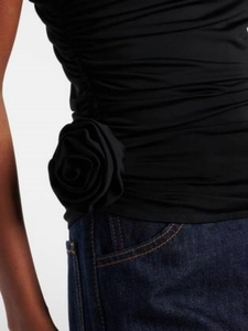 Detail eines schwarzen One-Shoulder-Tops mit 3D-Stoffrose und gerafftem Seitenteil