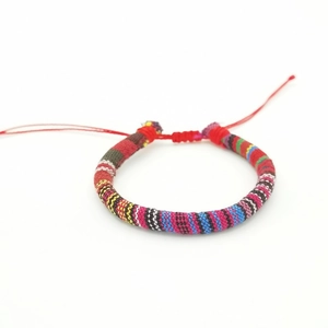 Detailed view of colorful Bohemian handmade woven surf bracelet with adjustable red knots