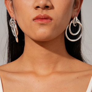 Polished silver geometric multi-layer intertwined loop earrings worn by a model