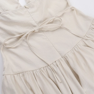 Détails du lien à la taille et du zip invisible sur une robe beige en lin avec plissés