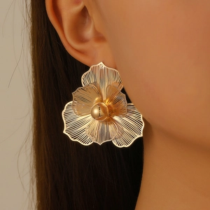 Close-up of elegant gold hollow flower earring with brushed texture on female model