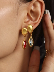 Détail de boucles d'oreilles dorées avec pierres précieuses marquise rouges et bleues