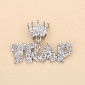 Macro shot of silver hip hop pendant featuring iced out TRAP letters and crown detail
