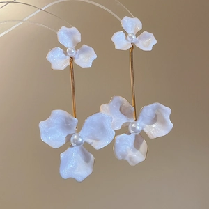 Detail of elegant gold flower earrings with white enamel petals and pearl centers