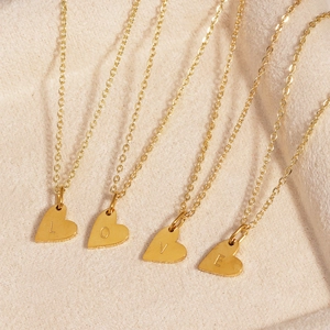 Quatre colliers à pendentif cœur doré avec gravure LOVE sur tissu beige soyeux