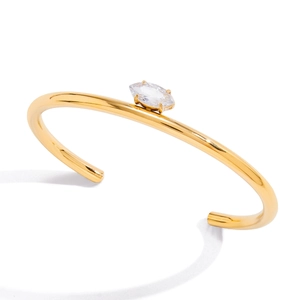 Close-up of polished gold-tone stainless steel open bangle with marquise zircon stone