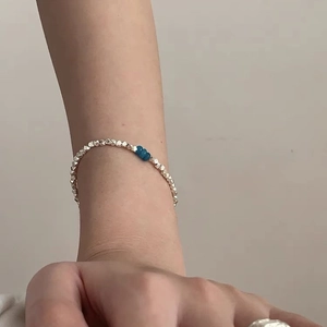 Close-up of minimalist silver bead bracelet with blue crystals worn on a female wrist