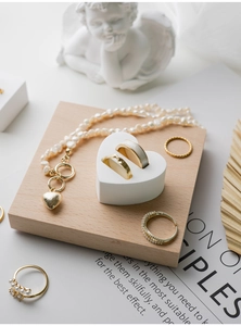 Macro shot of pearl necklace with gold heart pendant and assorted rings on a plaster display