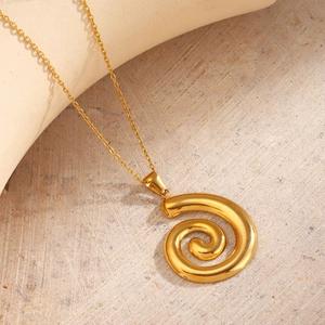 Goldene Kette mit Spiralanhänger auf beigem Grund bei sanfter Beleuchtung