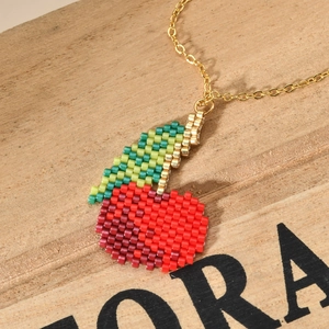 Bohemian colorful bead necklace featuring a handmade cherry pendant on a wooden background